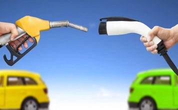 Automóvil eléctrico y auto concepto de gasolina. mano sosteniendo bomba de gasolina y conector para recarga de energía vía Shutterstock