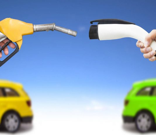 Automóvil eléctrico y auto concepto de gasolina. mano sosteniendo bomba de gasolina y conector para recarga de energía vía Shutterstock